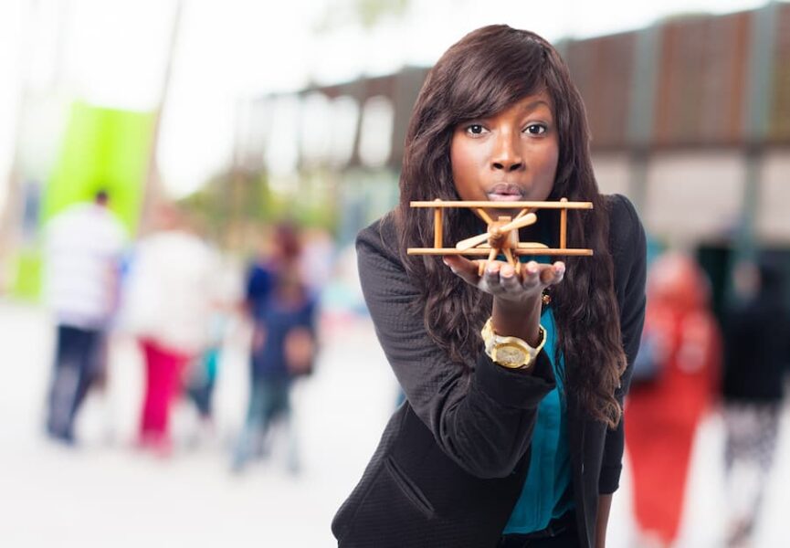 Woman holding a wooden plane, reflecting on ambition and balance.